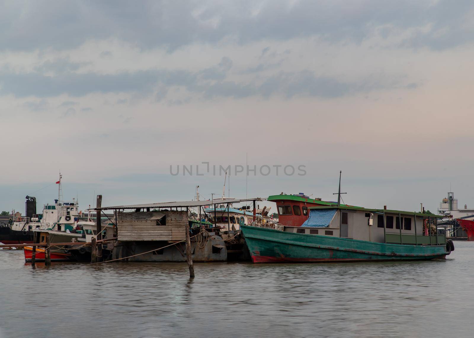 Bangkok, Thailand - 04 Jan 2021 : A small cargo ship parked in front of the small pier at Chao Phraya river. Selective focus.