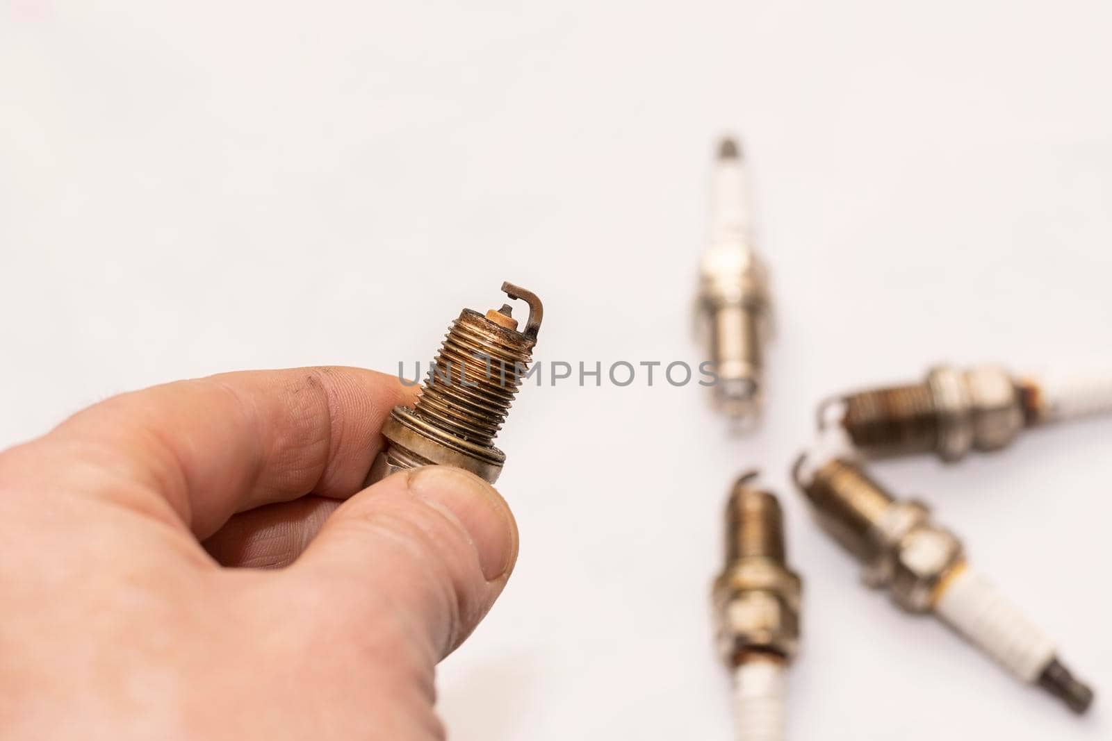 a man's hand holds an old worn out gasoline car spark plug by jk3030