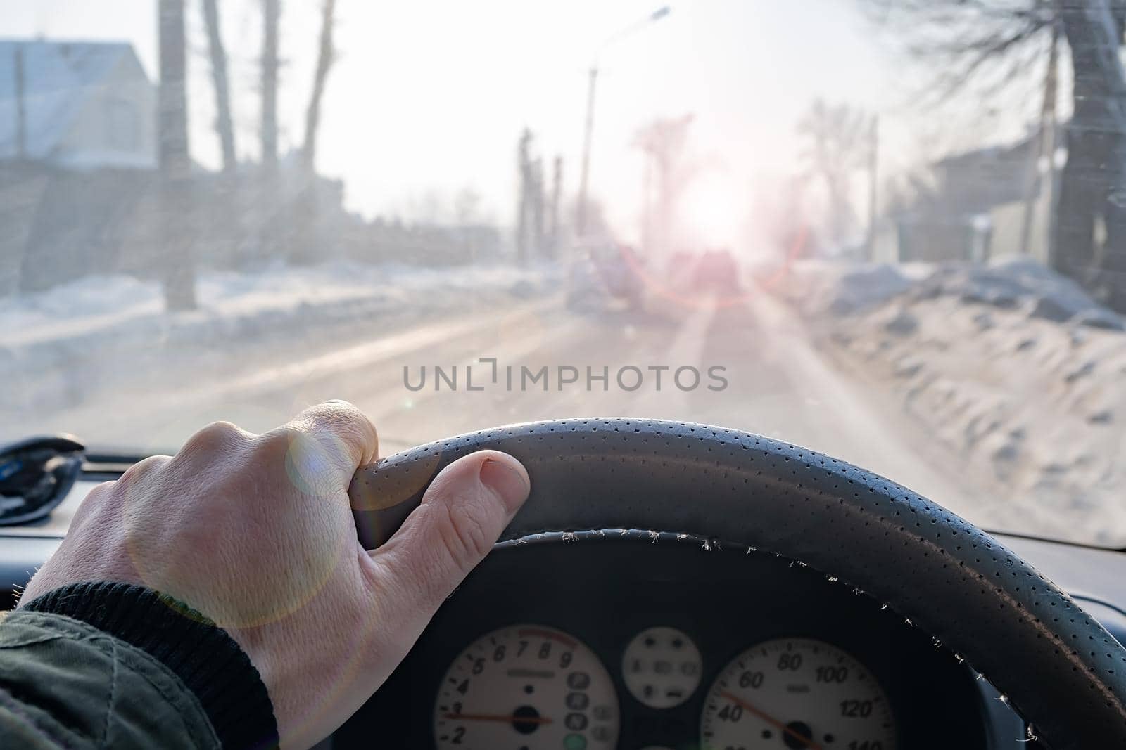 hand of a man on the steering wheel of a car that is driving on a slippery road by jk3030