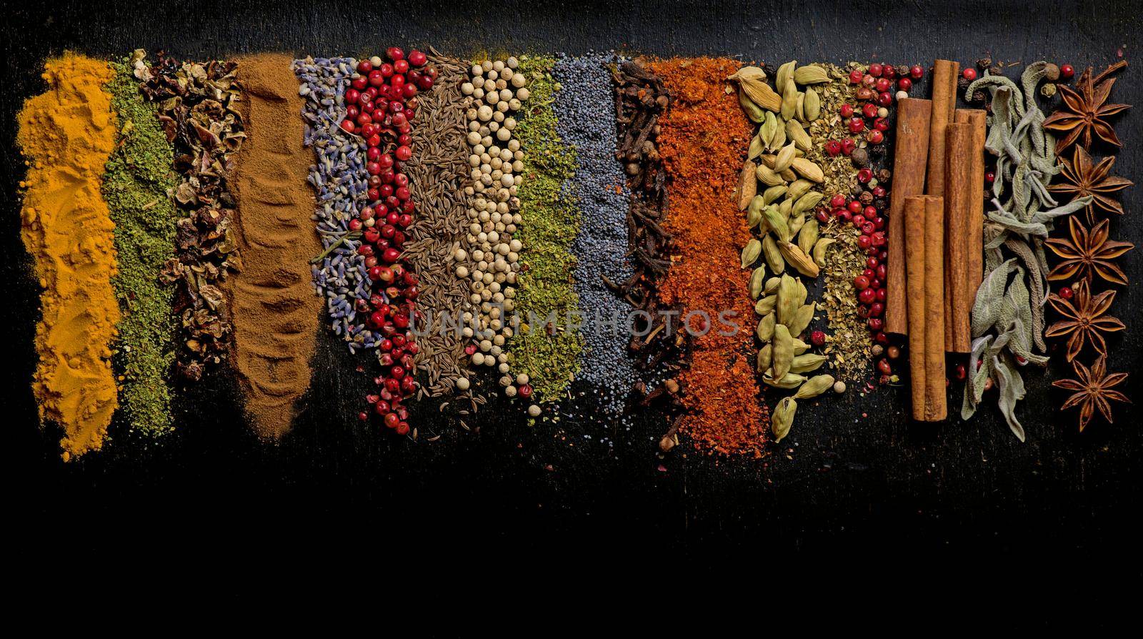 Powder spices on spoons in black wooden table background.