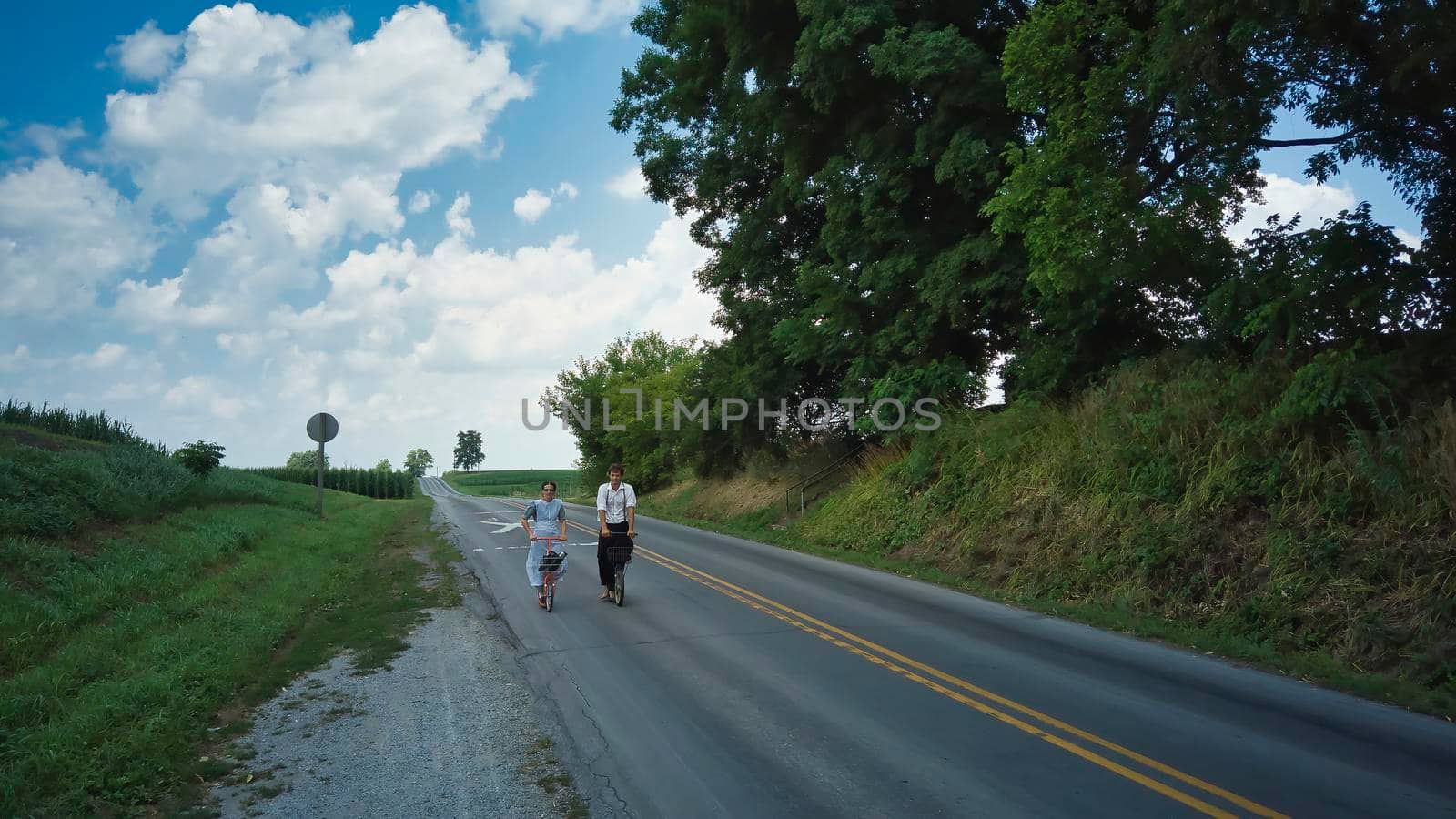 Ronks, Pennsylvania, July 2020 - Two Amish Teenagers One Boy and One Girl on Scooters on a Summer Day