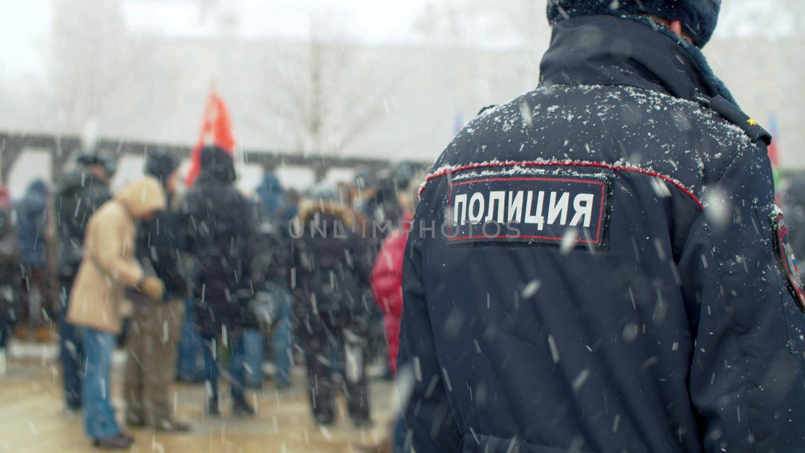 Two cops at a demonstration under the snowfall. Protest rally against construction, for maintaining parks. Text on jacket - police