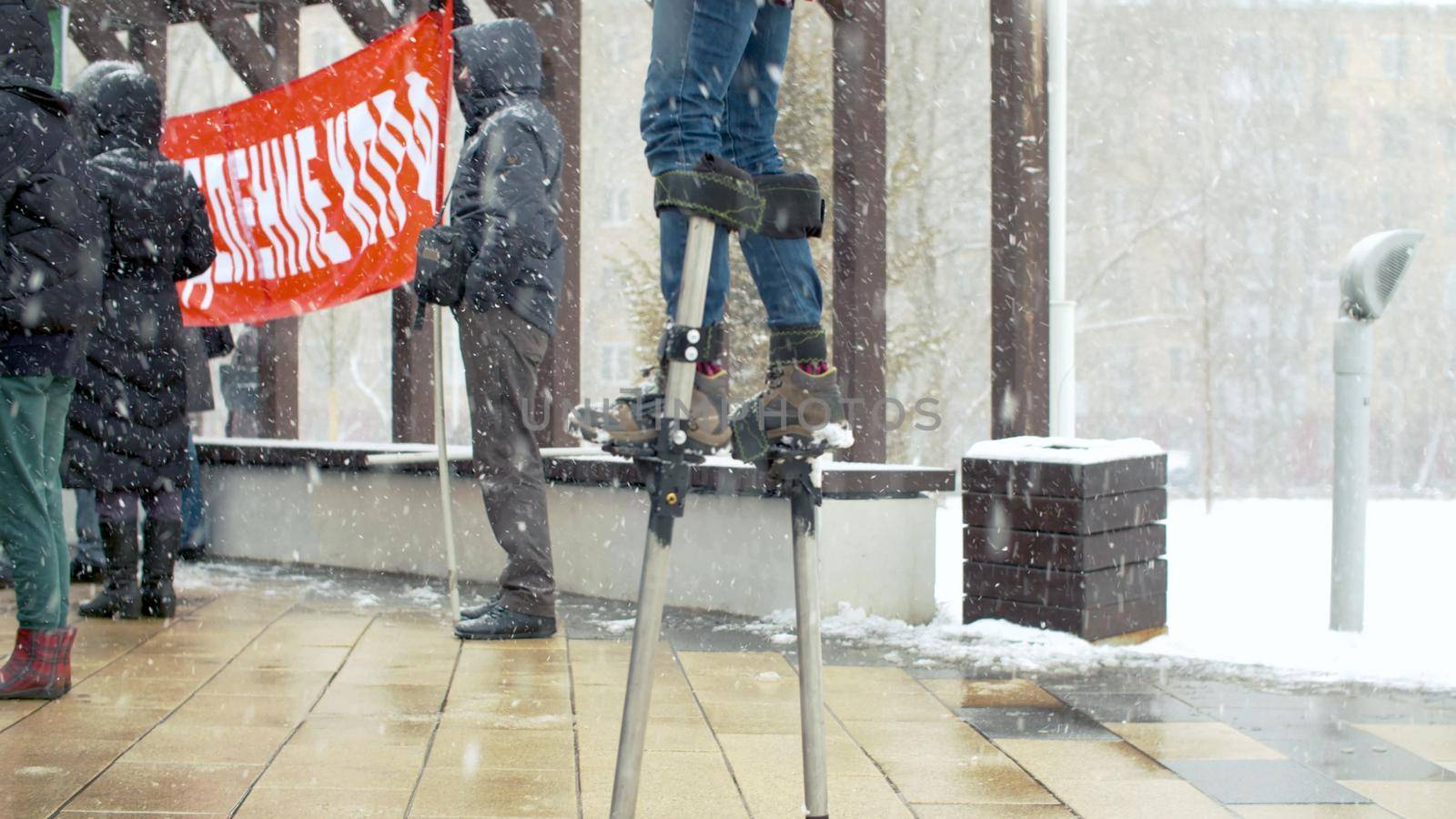 Girl on stilts under the snowfall at a protest rally against construction. Make Your Voice Heard