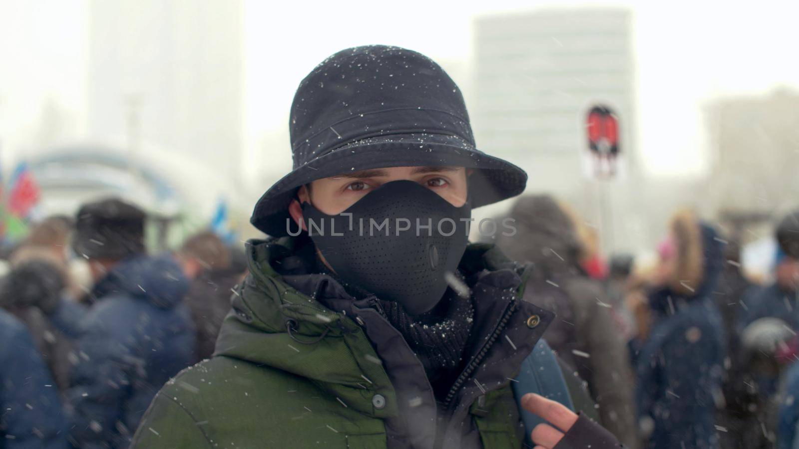 Close up portrait of a man wearing special protective mask on background of the rally crowd. Coronavirus epidemic in Moscow. Concept of health and safety life. COVID-19 pandemic