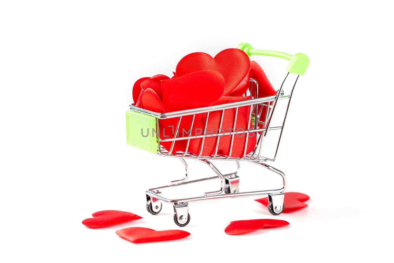 A toy cart from the supermarket filled with red hearts isolated on white background, the concept of love and Valentine's Day.
