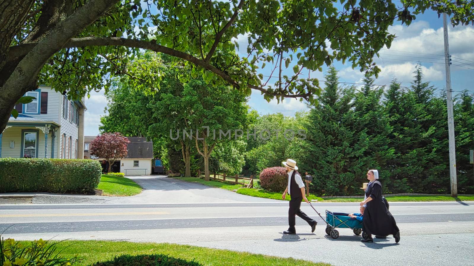 Gordonville, Pennsylvania, June 2020 -An Amish Family Walking along a Country Road Pulling a Wagon with a Small Child in it