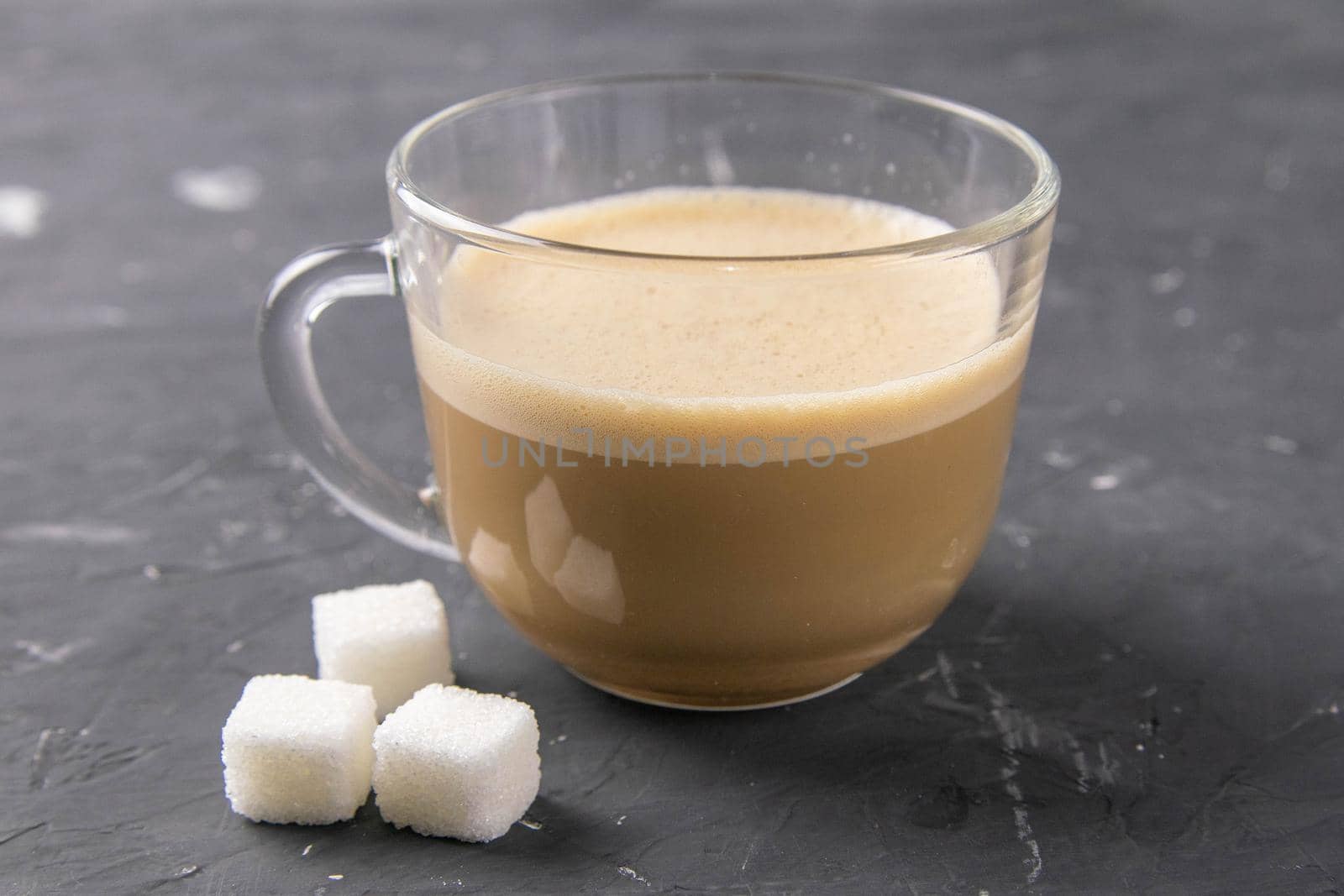 A Cup of coffee and sugar cubes on a dark background. Close-up by uspmen