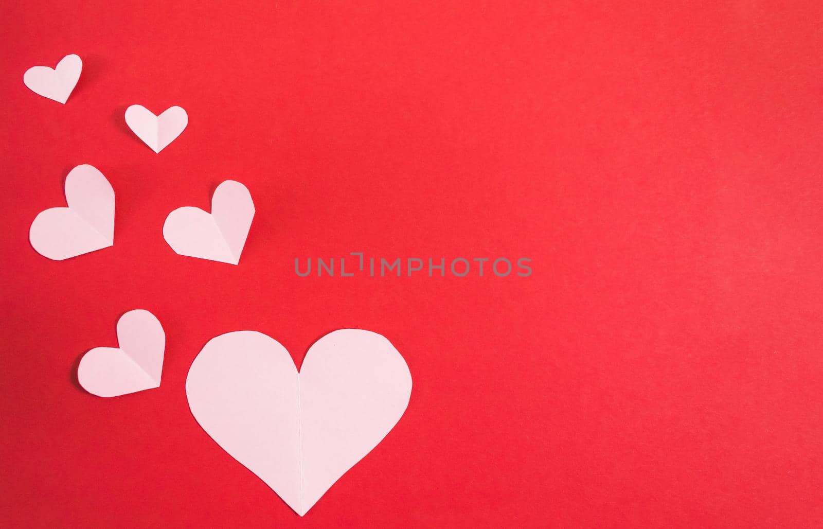 Paper hearts of different sizes on a red background. Abstract background with paper cut shapes. Sainte Valentine, mother's day. birthday greeting cards, invitations. Template for design. Copy space.