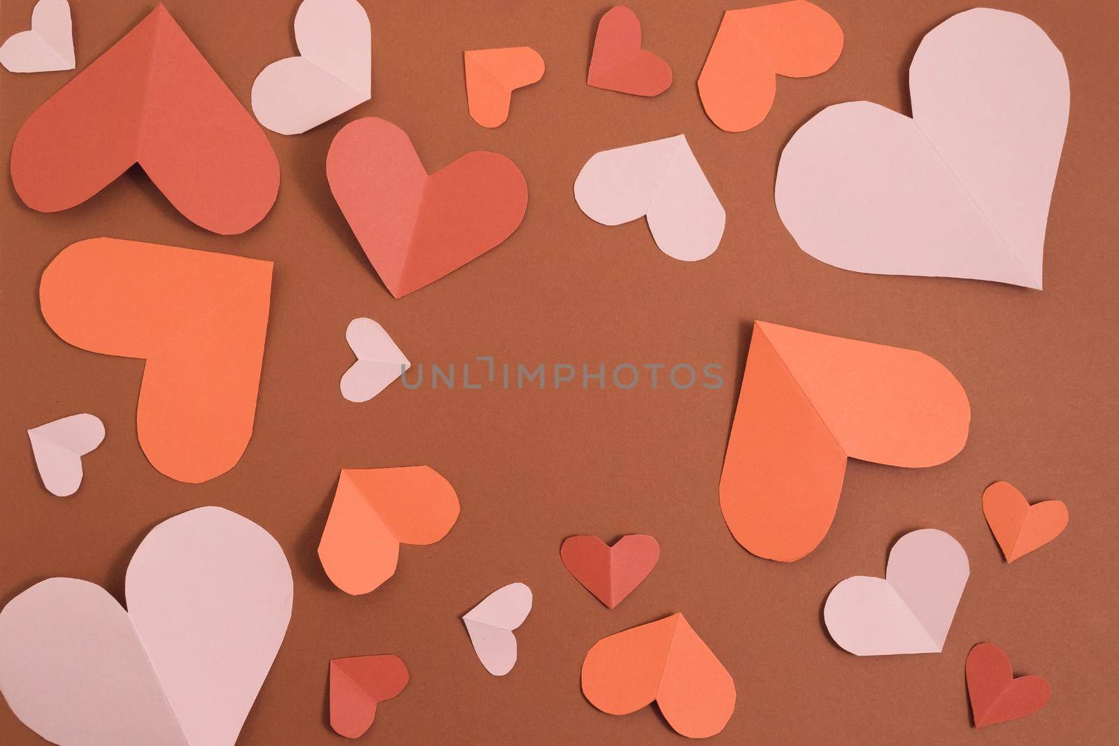Valentine's day background. Pink, red, burgundy hearts of different sizes laid out in a circle on a brown background. Layout for postcards and congratulations. Flat lay, top view, copy space by Alla_Morozova93