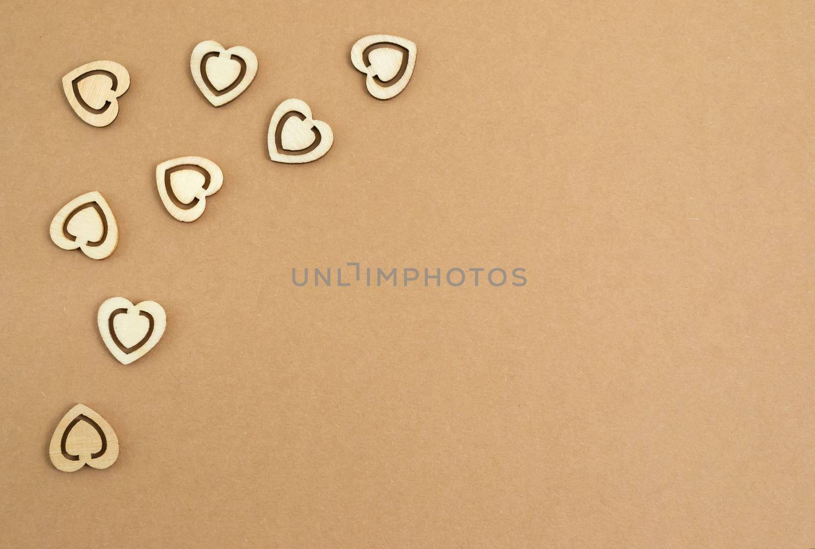 Wooden hearts on a pastel craft paper background. Abstract background with wood cut shapes. Sainte Valentine, mother's day, birthday greeting cards, invitations. Copy space.