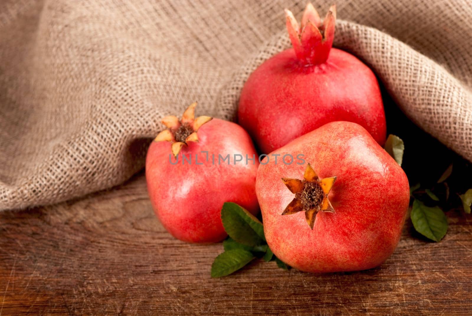 ripe pomegranate with leaves on a wooden board by aprilphoto