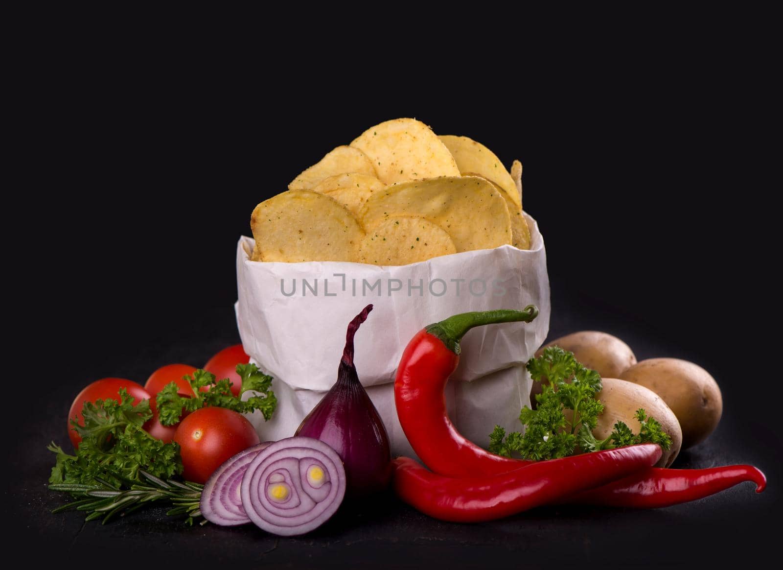 Potato chips on a dark wooden board. Fast food. Dark background. by aprilphoto