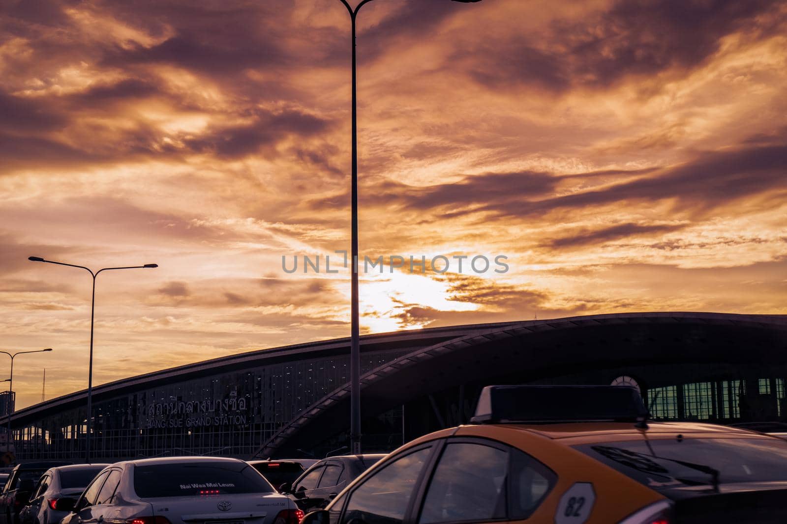 BANGKOK, THAILAND-OCTOBER 30, 2020 : Traffic jam in front off Bang Sue Grand Station with golden sunset sky and street lamp light. Many of car and Taxi on the road near grand station building. 