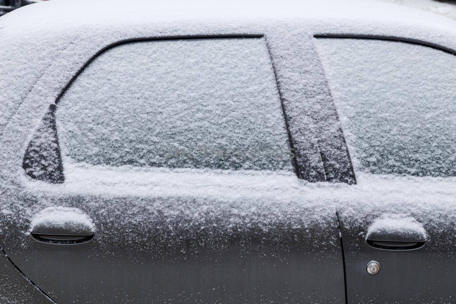 black car covered with snow at cloudy day light - close-up full frame side view