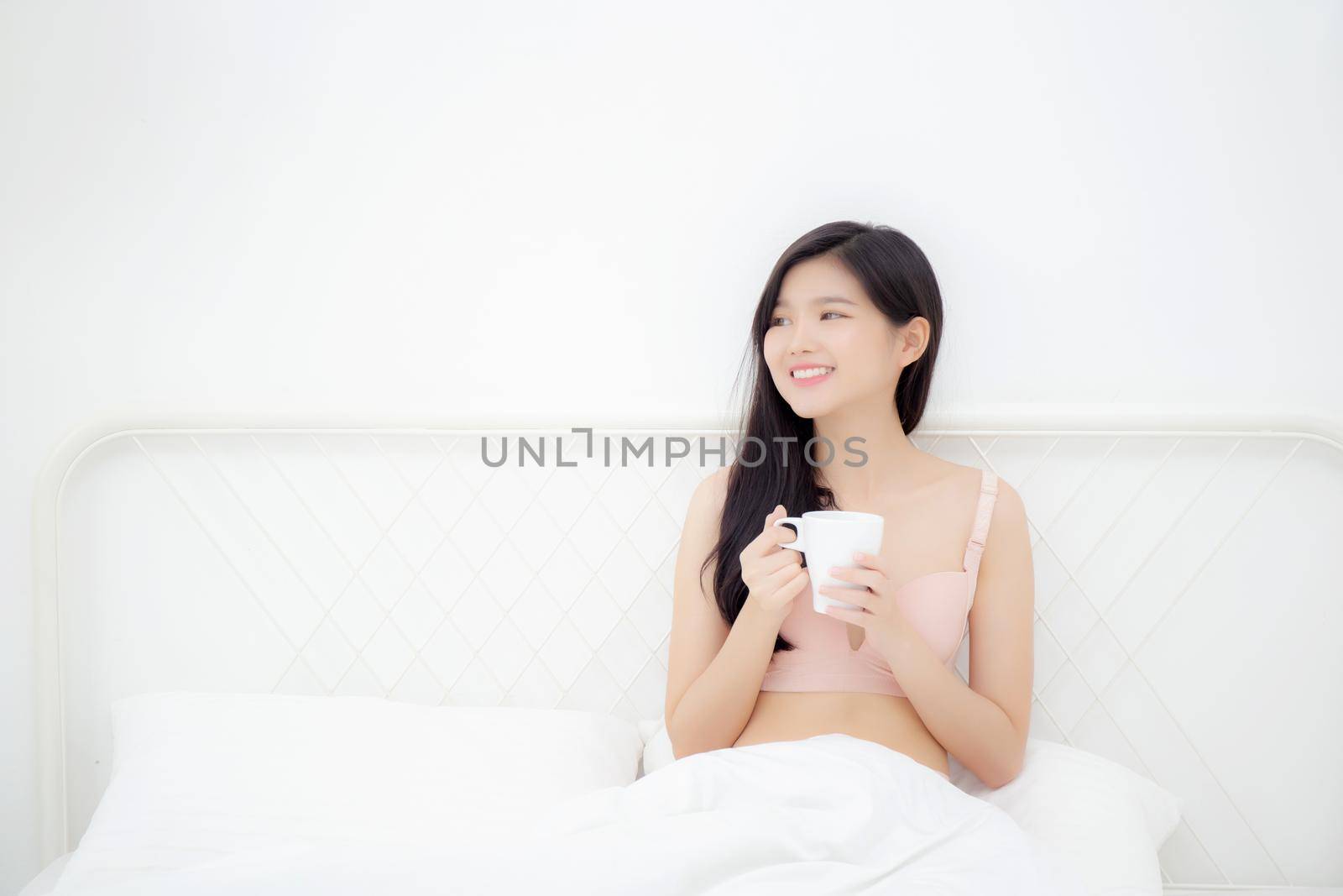 Beautiful young asian sexy woman in underwear drinking coffee in the morning on bed at bedroom, asia girl with seductive figure fit drinking beverage for relax after wake up, lifestyle concept.