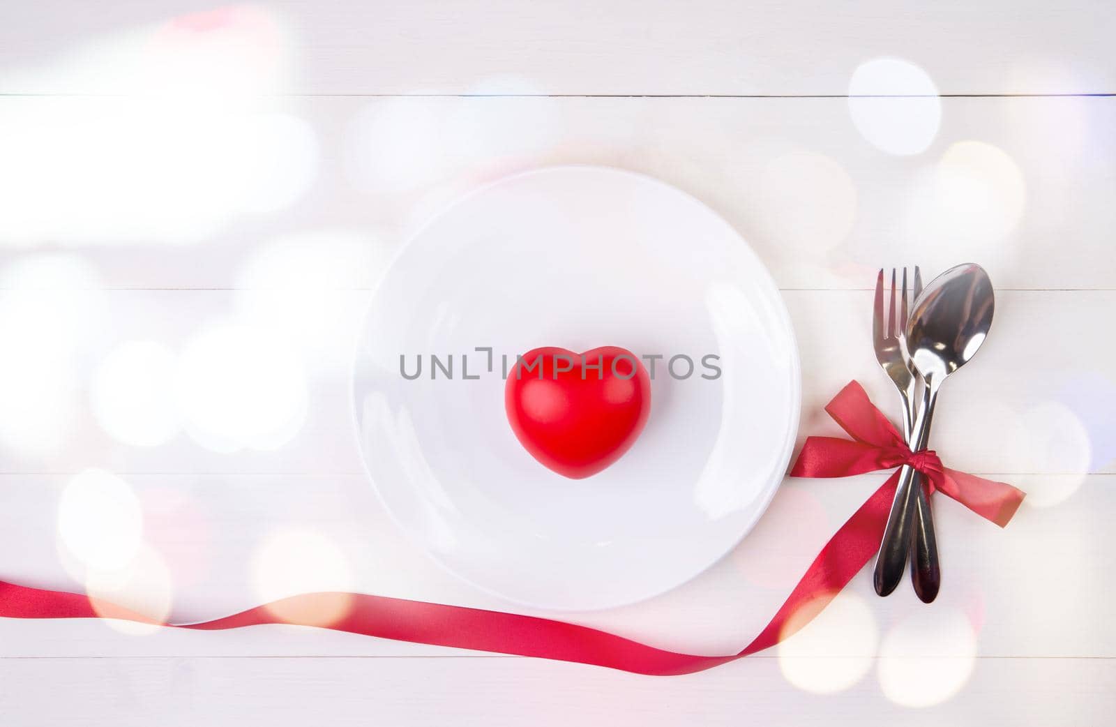 Valentine day, heart shape on dish and utensil with bow for dinner on wooden table, spoon and fork with ribbon on desk, anniversary and celebration of love, copy space, top view, holiday concept.