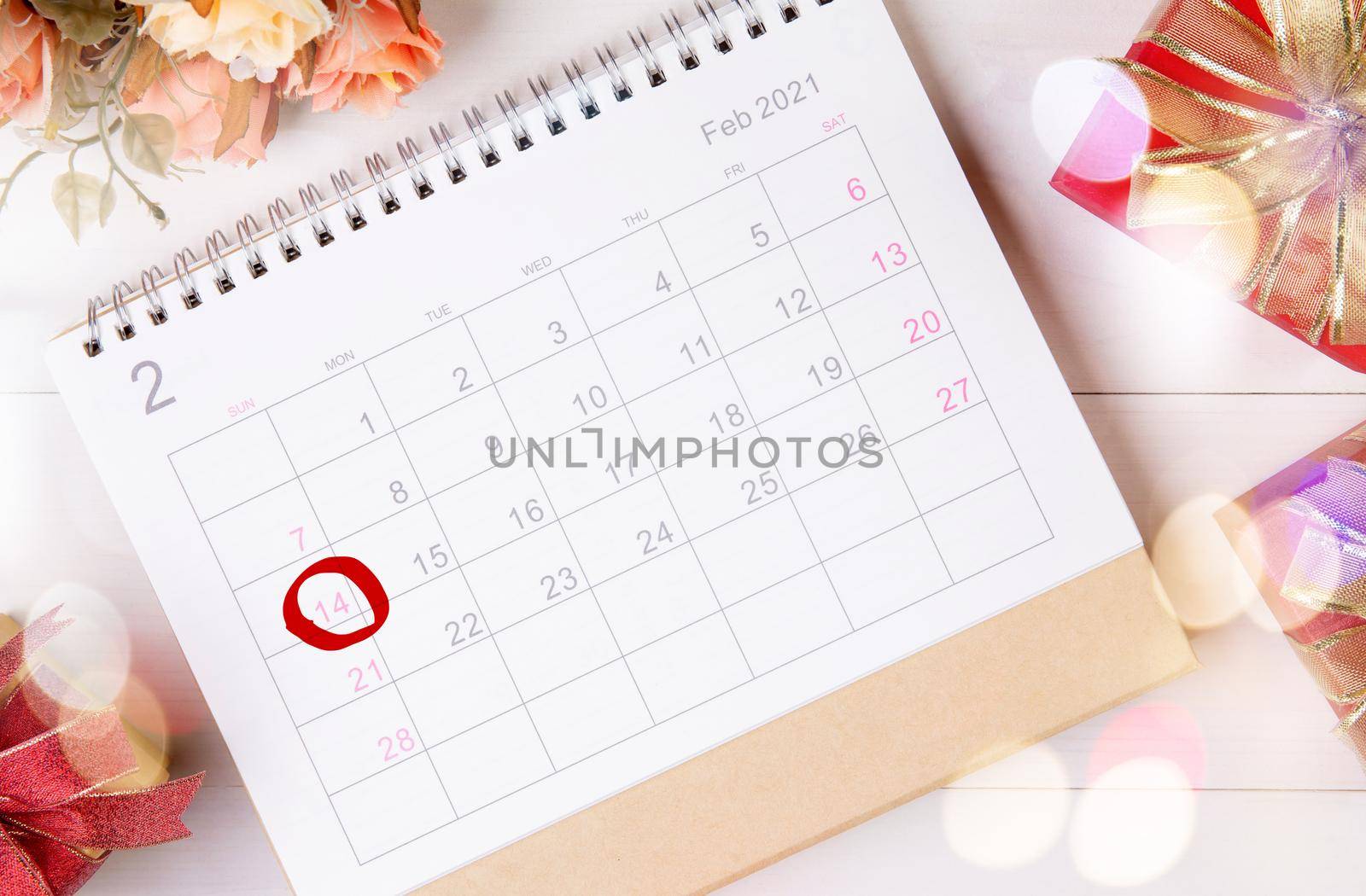 Calendar and flower with memo 14 February Valentine day on desk with blur bokeh background, reminder for surprise of love, romance and sweet, celebration and decoration, top view, holiday concept. by nnudoo