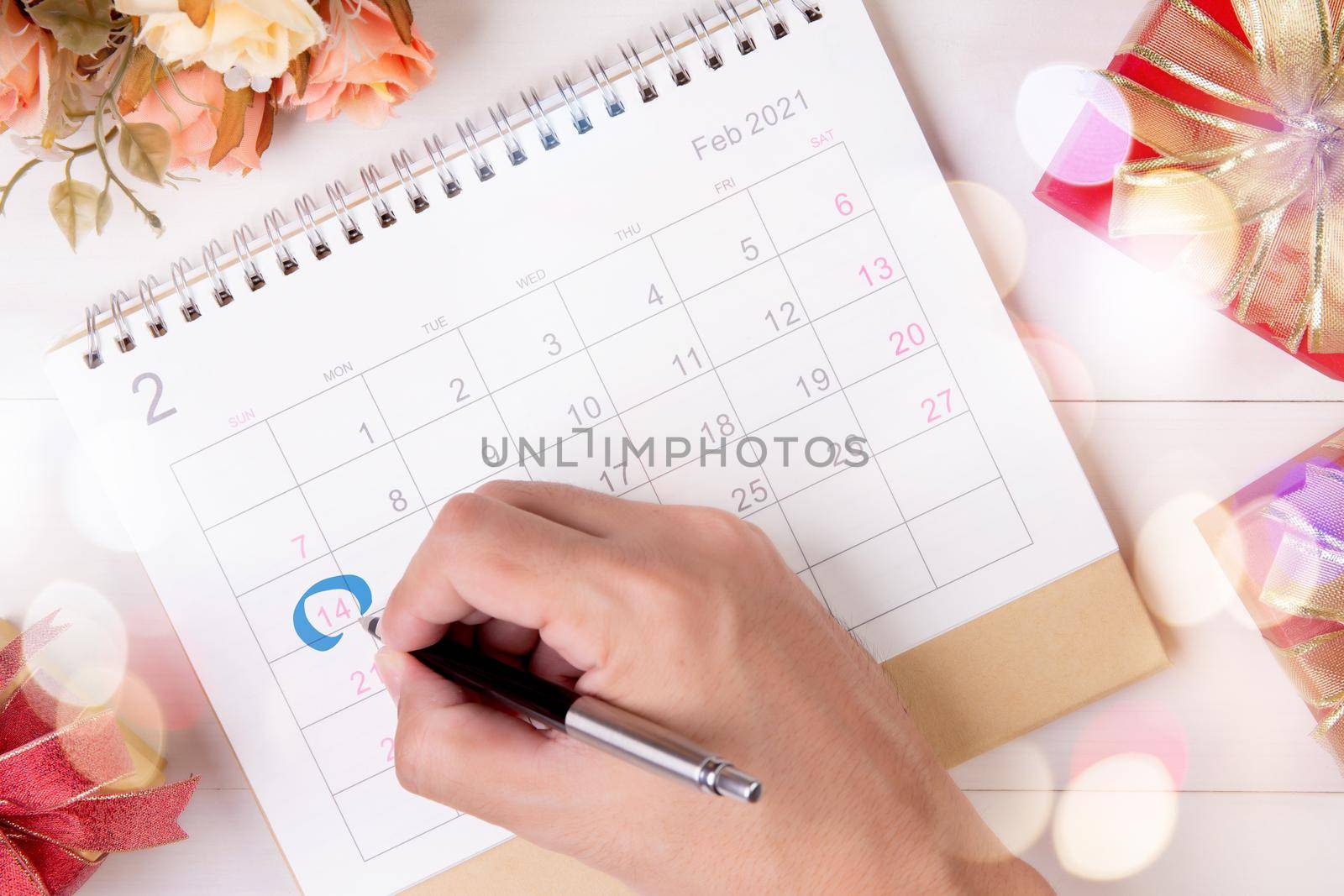 Hand writing with marker on calendar reminder with memo 14 February Valentine day on desk with blur bokeh background, appointment for plan surprise of love and romance, top view, holiday concept. by nnudoo