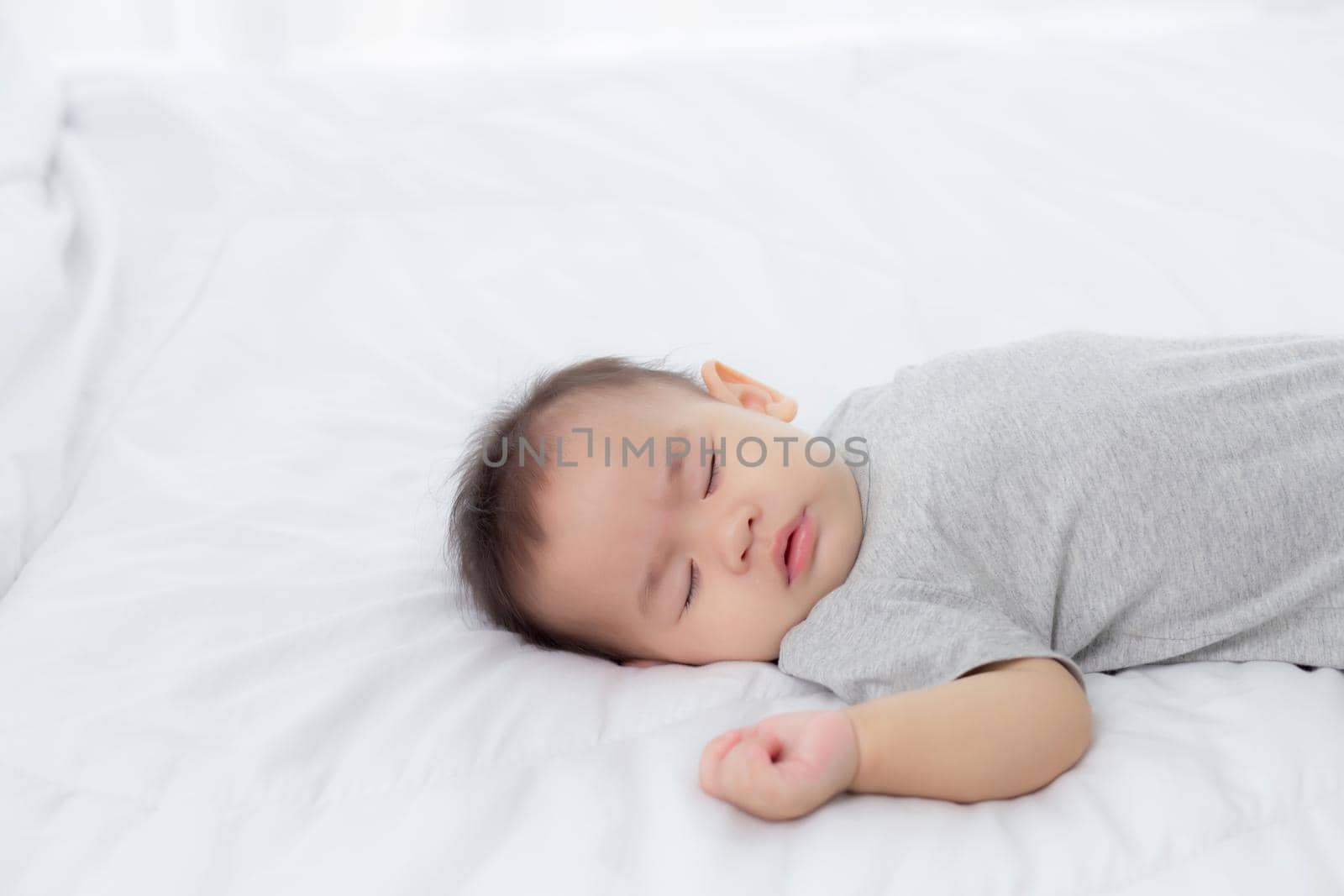 Portrait of asian little baby girl sleeping on bed in the bedroom at home, newborn napping with cozy and relax, infant innocence in bedtime, happy toddler cute, growth of child and emotion, indoors.