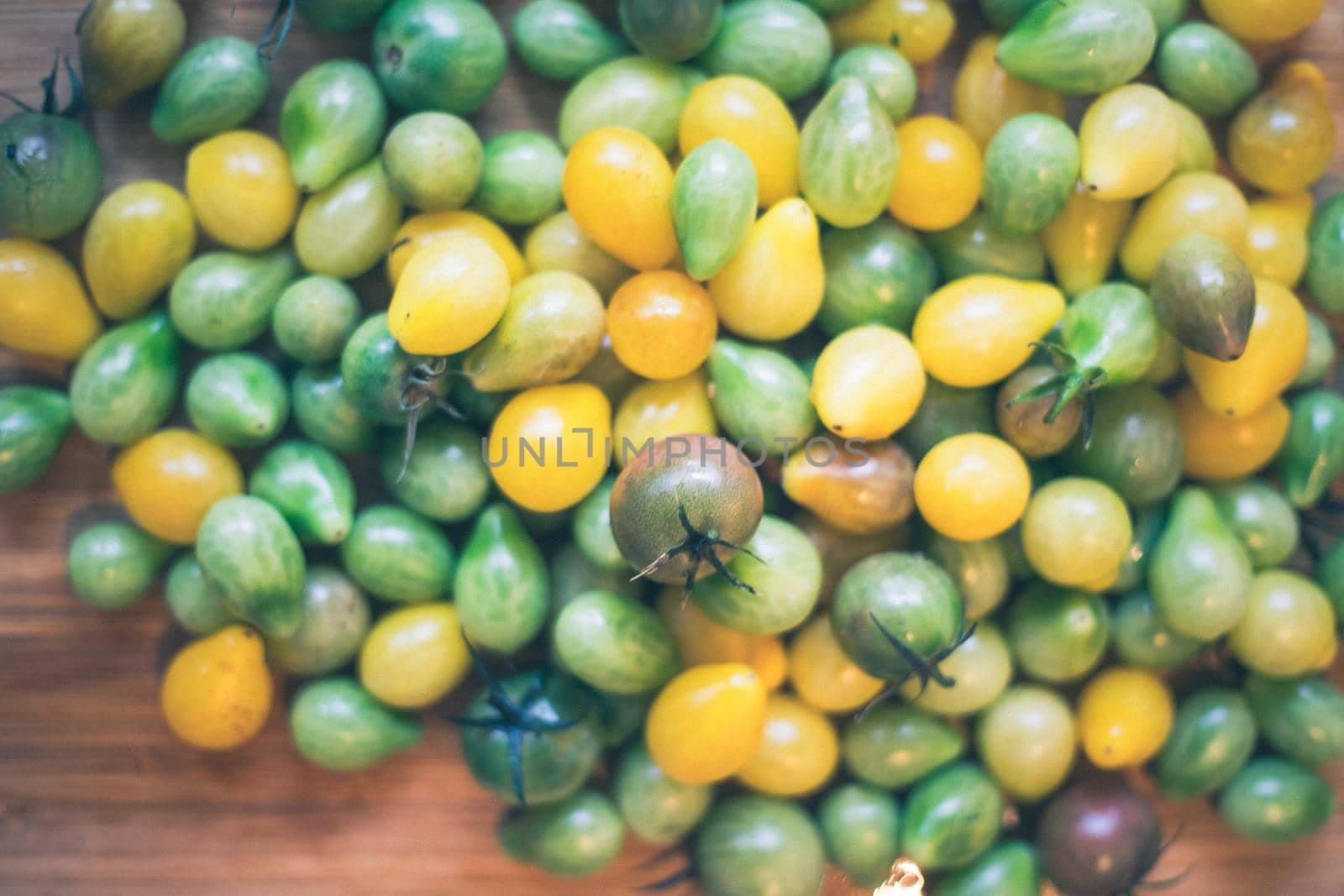 Close up of cocktail tomatoes on wooden plate, yellow and green