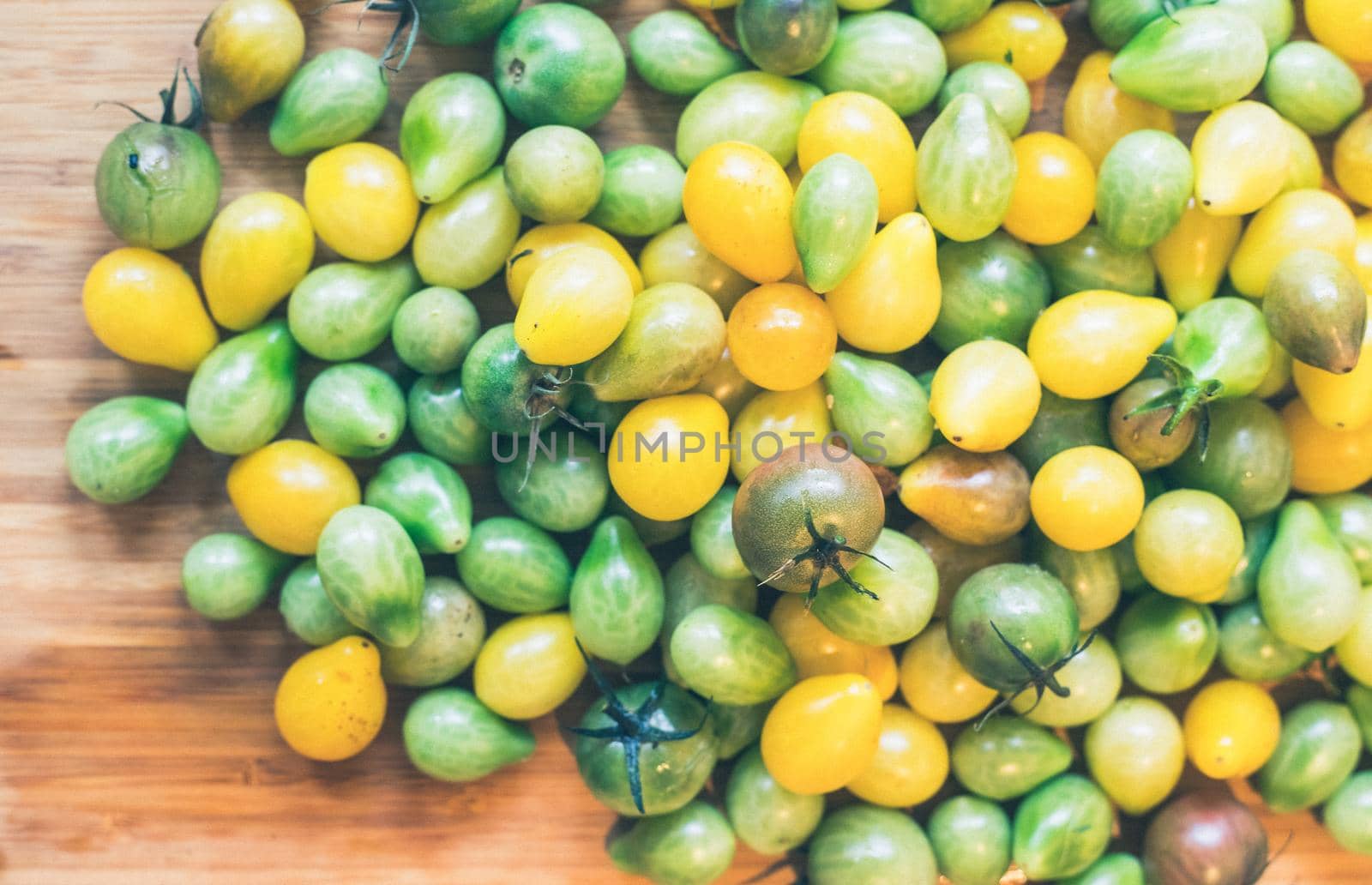 Close up of cocktail tomatoes on wooden plate, yellow and green
