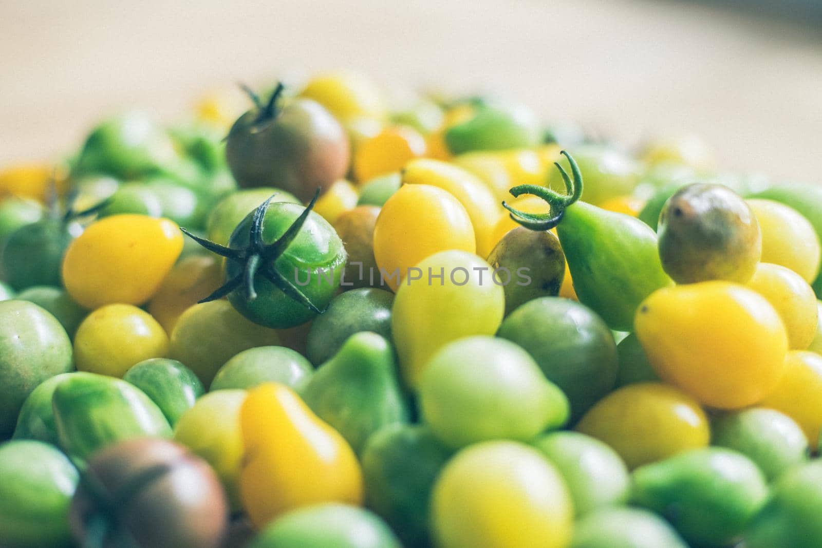 Close up of cocktail tomatoes on wooden plate, yellow and green