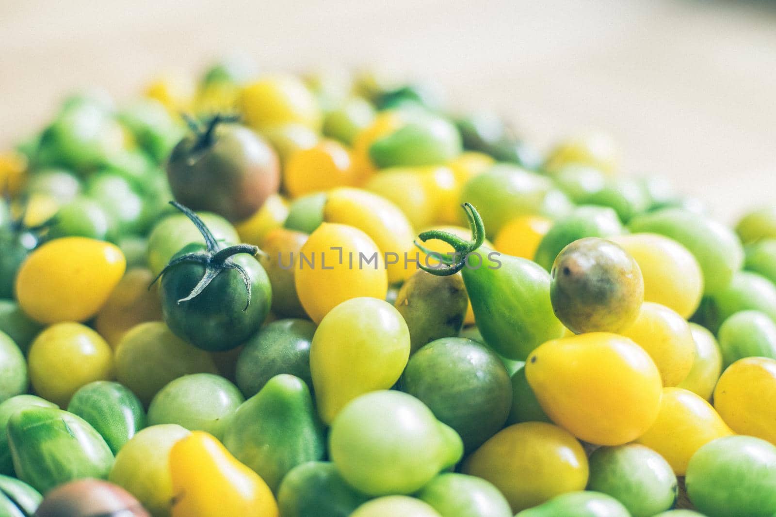 Close up of cocktail tomatoes on wooden plate, yellow and green