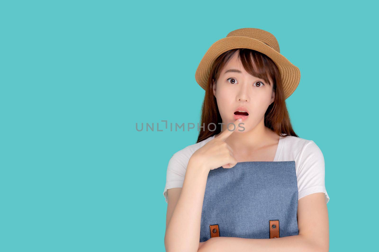 Beautiful portrait young asian woman wearing hat smiling and thinking idea with holding backpack to travel summer trip in holiday in vacation isolated blue background, tourist asia girl is having bag.