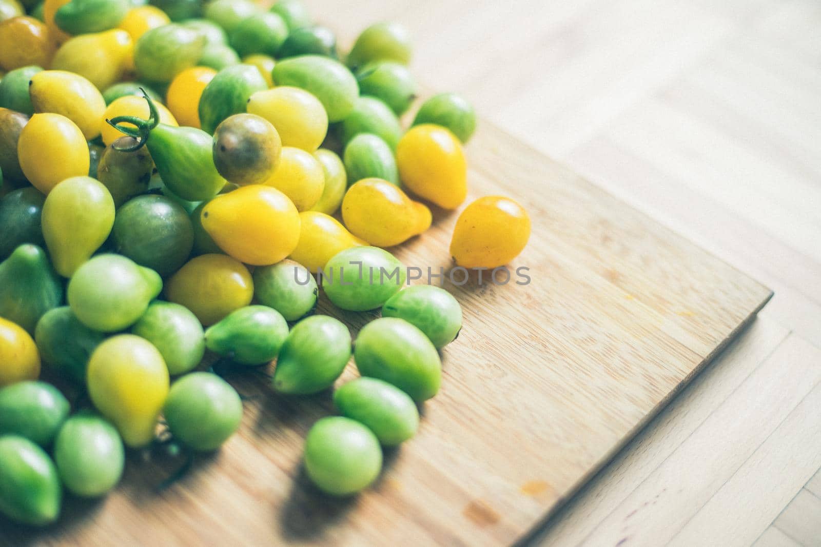 Close up of cocktail tomatoes on wooden plate, yellow and green