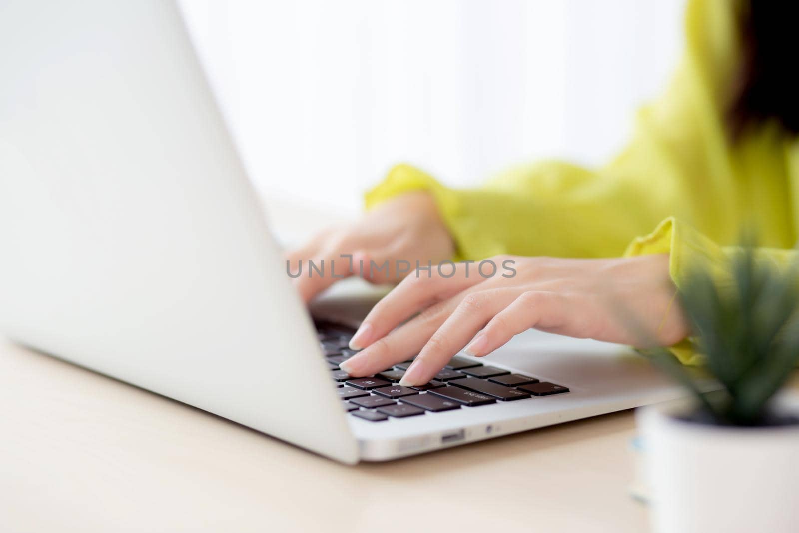 Closeup of hand young asian businesswoman working on laptop computer on desk at home office, freelance looking and typing on notebook on table, woman studying online, business and education concept.