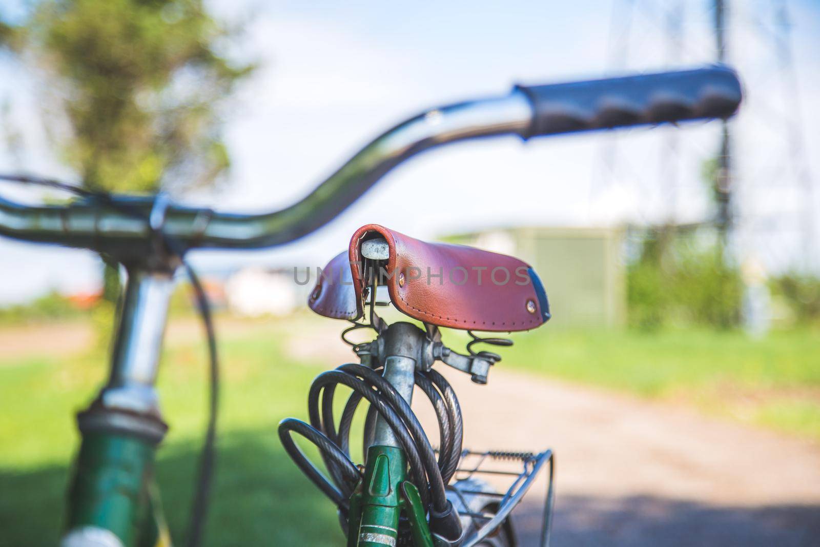 Closeup picture of brown vintage bicycle seat outdoors, blurred background