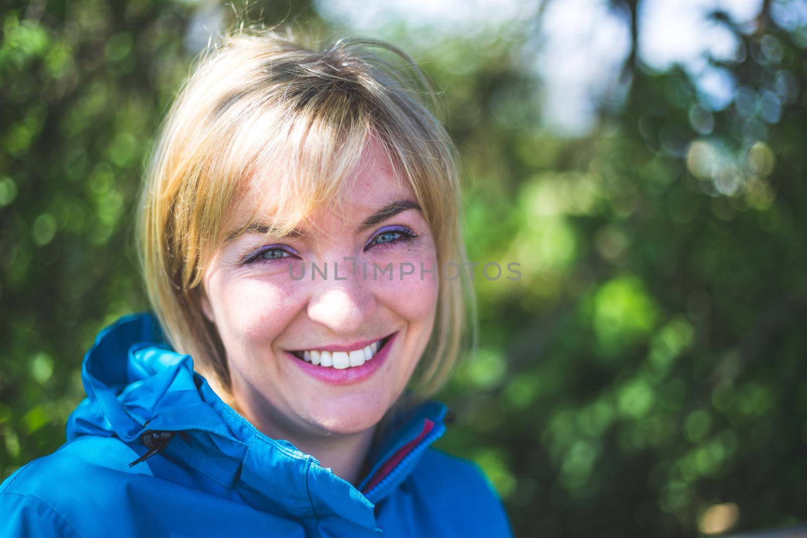 Smiling outdoors in spring. Portrait of smiling blonde girl outdoors by Daxenbichler