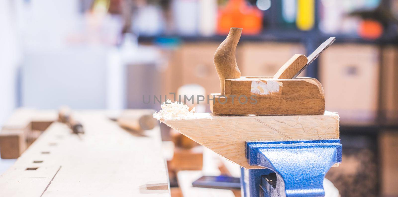 Home handyman using a plane for smoothing down a piece of timber by Daxenbichler