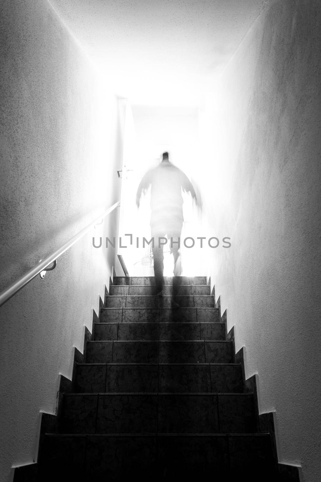 Man is going up on basement stairs with balustrade. Natural bright sunlight.