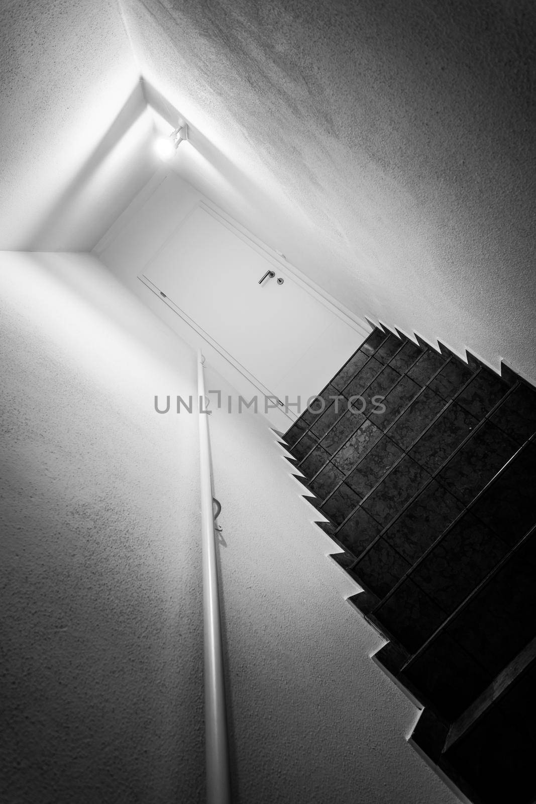 Basement stairway with railing. White door closed by Daxenbichler