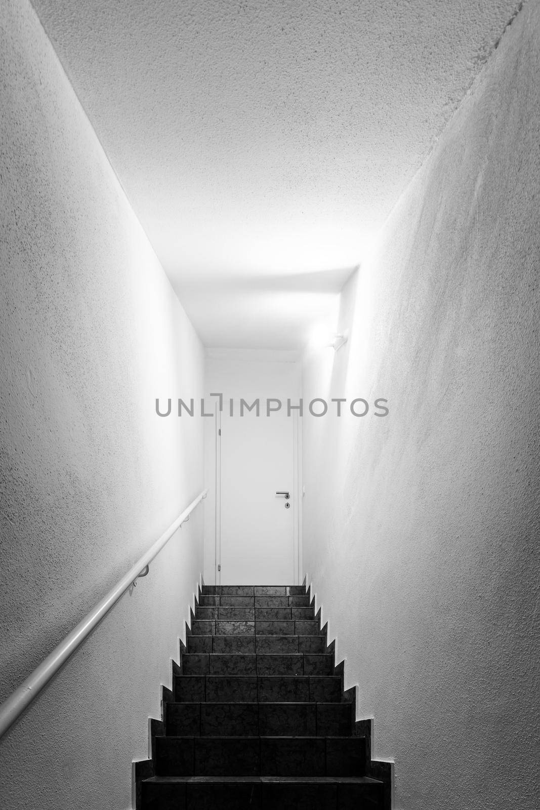 Basement stairway with railing. White door closed by Daxenbichler