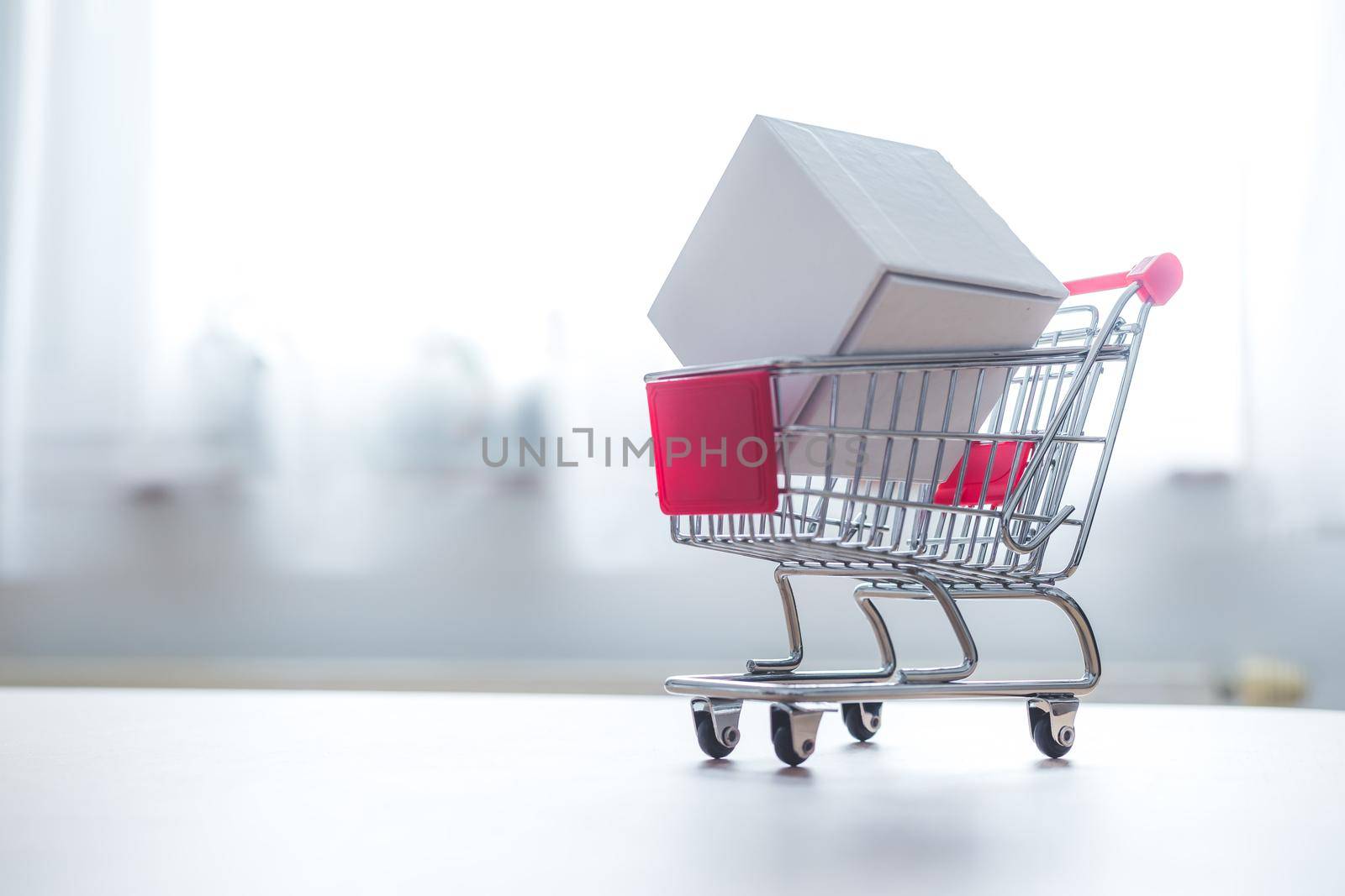 Online-Shopping and parcel service concept: Miniature shopping cart and white box