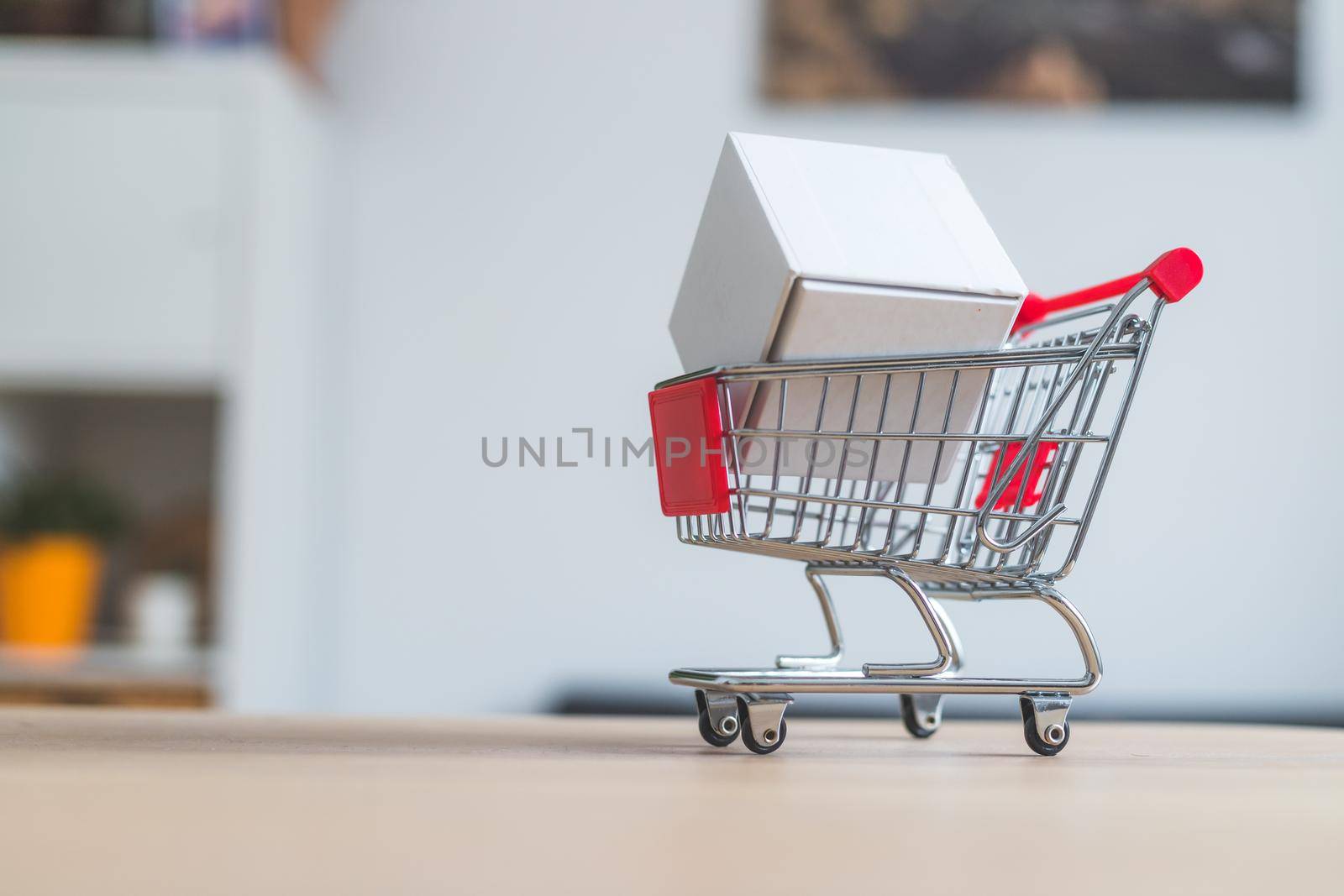 Online-Shopping and parcel service concept: Miniature shopping cart and white box