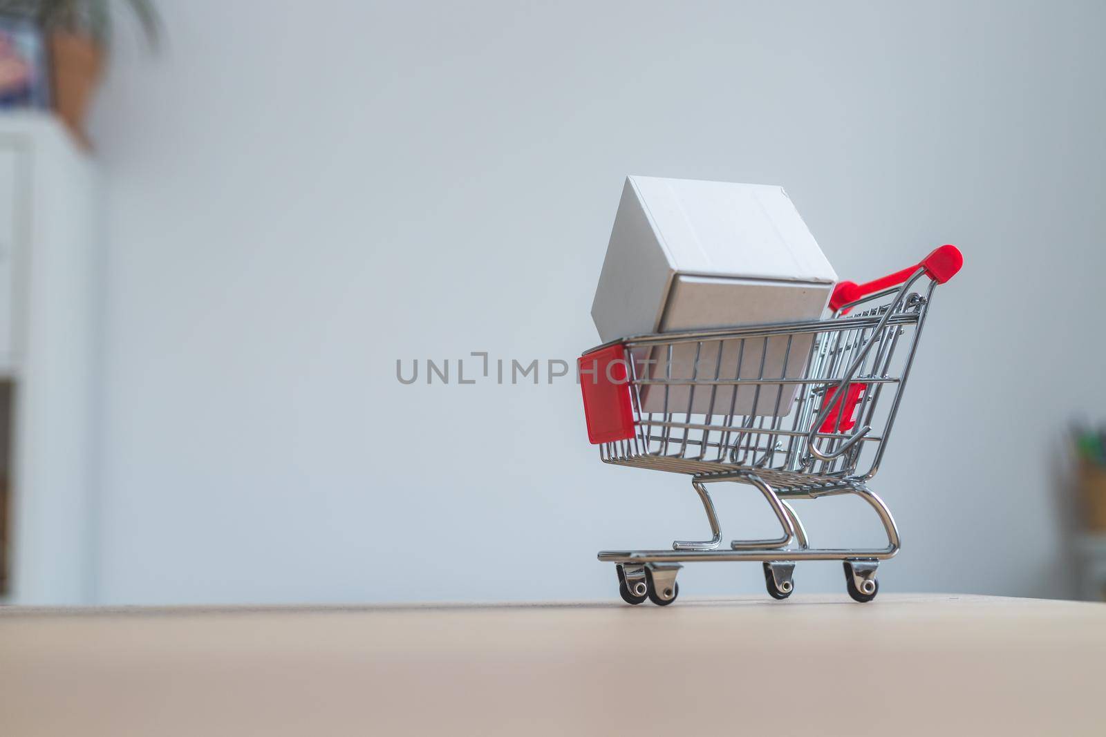 Online-Shopping and parcel service concept: Miniature shopping cart and white box