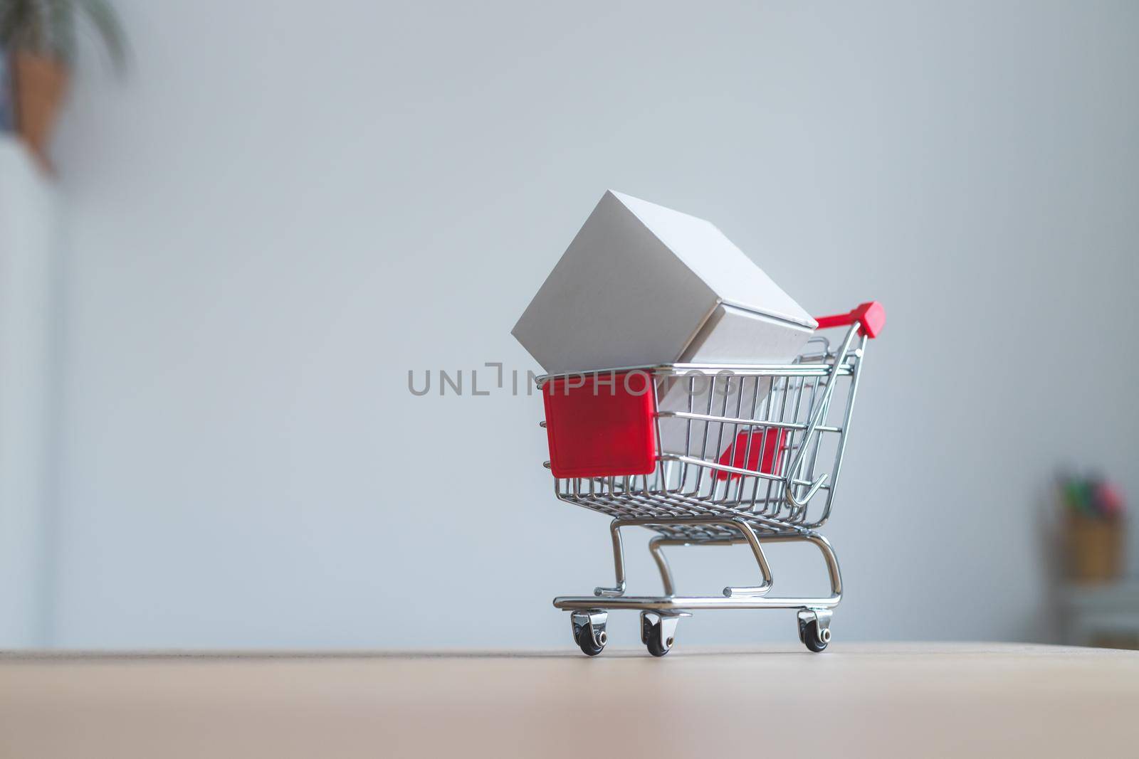 Online-Shopping and parcel service concept: Miniature shopping cart and white box