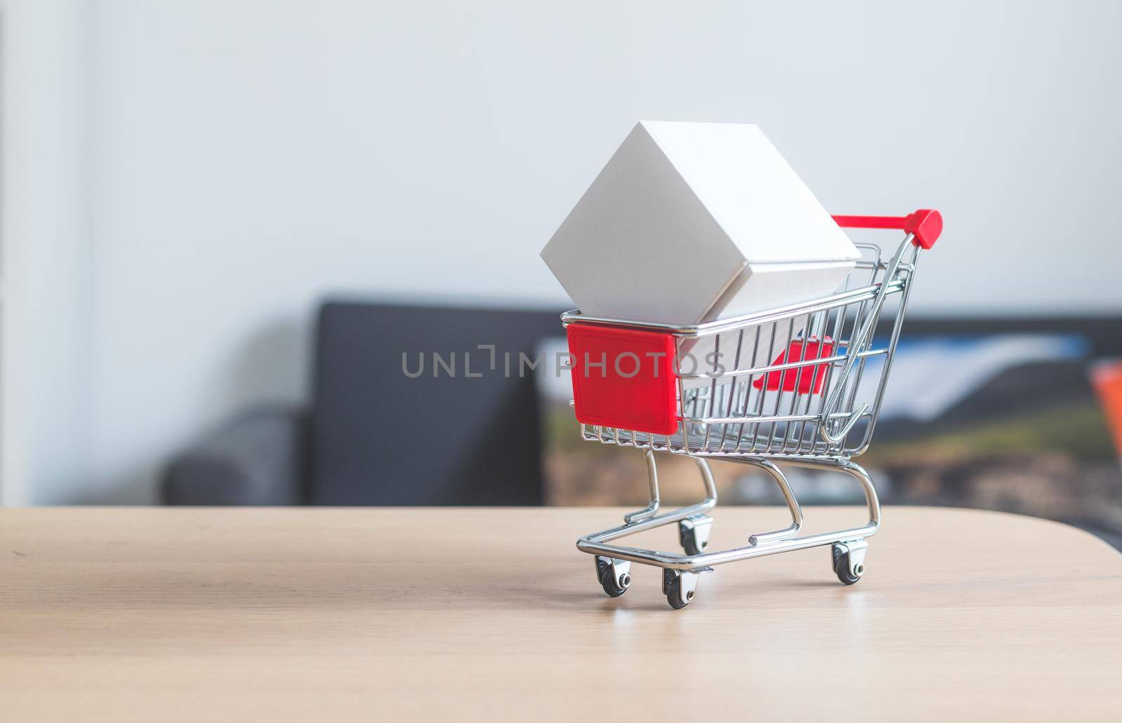 Online-Shopping and parcel service concept: Miniature shopping cart and white box