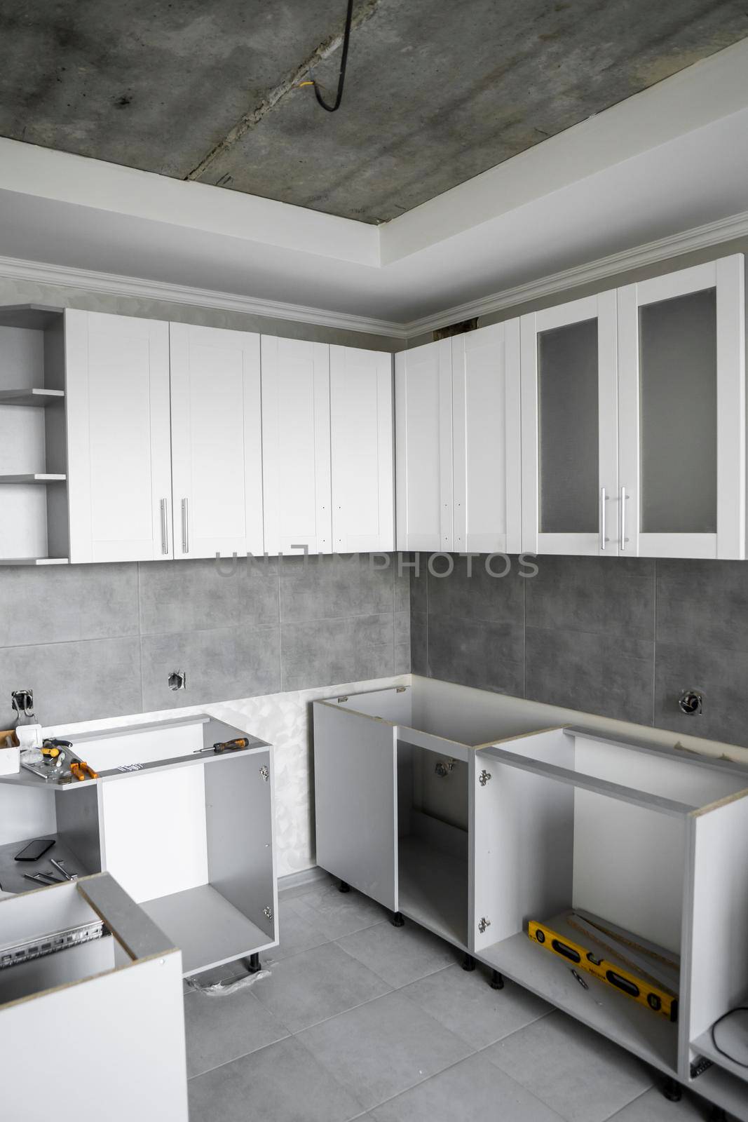 Custom kitchen cabinets installation with a furniture facades mdf. Gray modular kitchen from chipboard material on a various stages of installation. A frame furniture fronts mdf profile. by vovsht