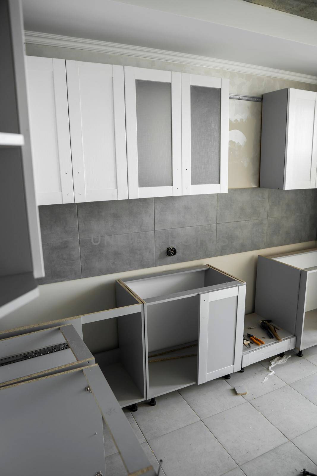 Custom kitchen cabinets installation with a furniture facades mdf. Gray modular kitchen from chipboard material on a various stages of installation. A frame furniture fronts mdf profile. by vovsht