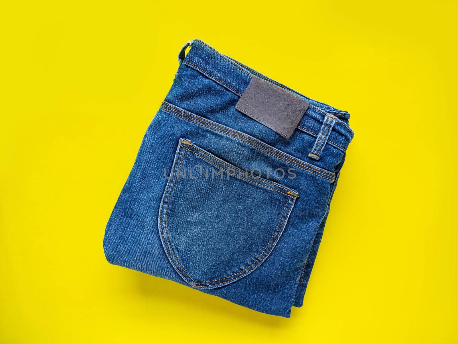 Blue pants Neatly folded See the details of the fabric Put on a yellow background