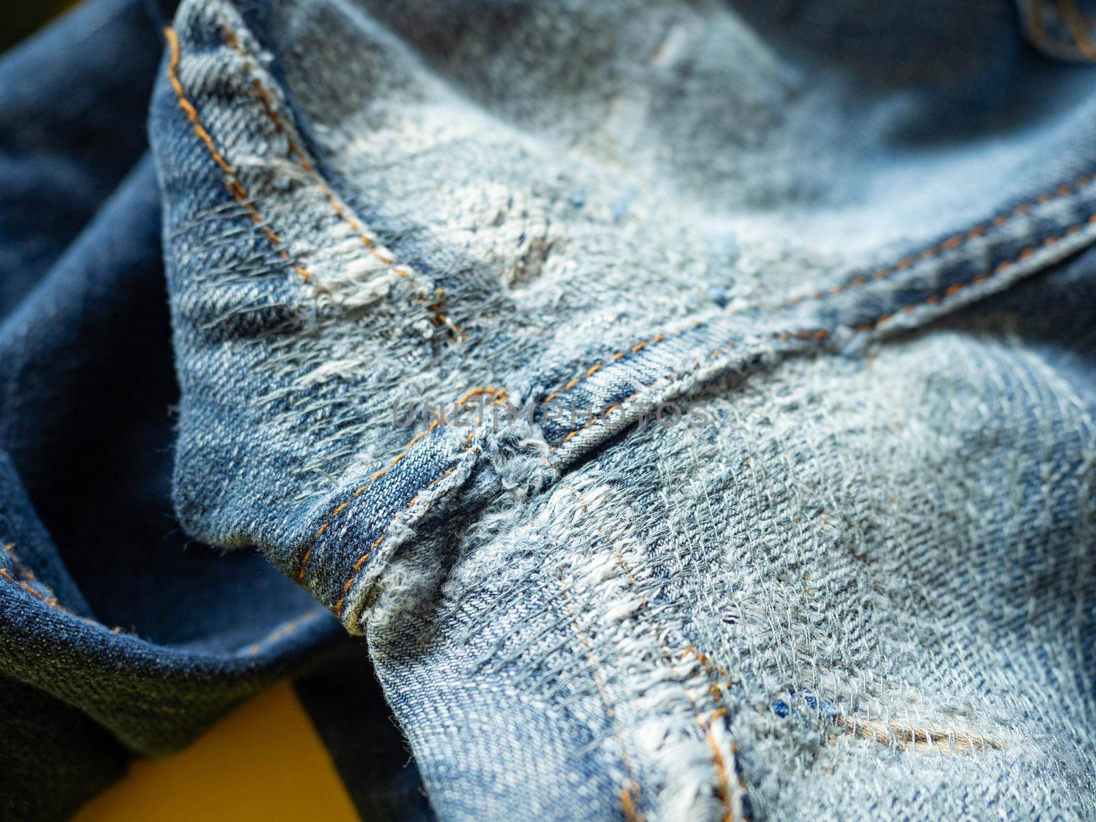 Blue jeans that have been repaired on the gusset. Placed on a yellow background. by Kulpreya