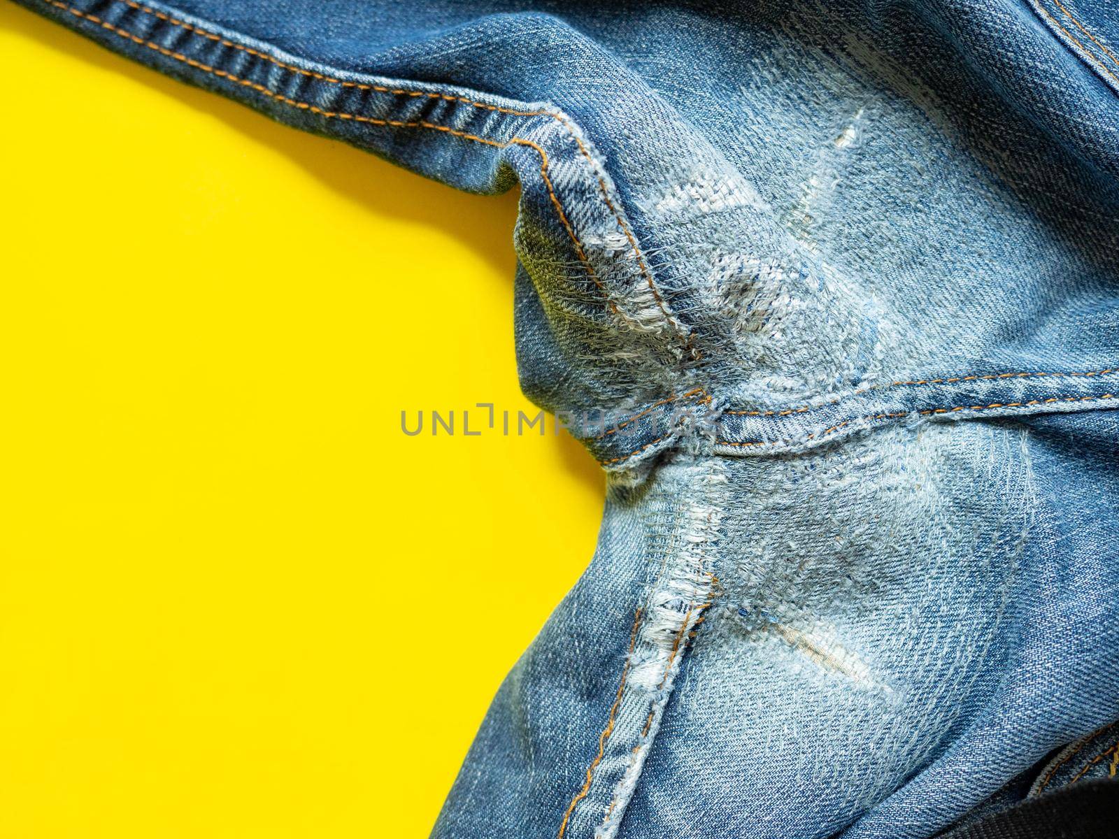 Blue jeans that have been repaired on the gusset. Placed on a yellow background. by Kulpreya