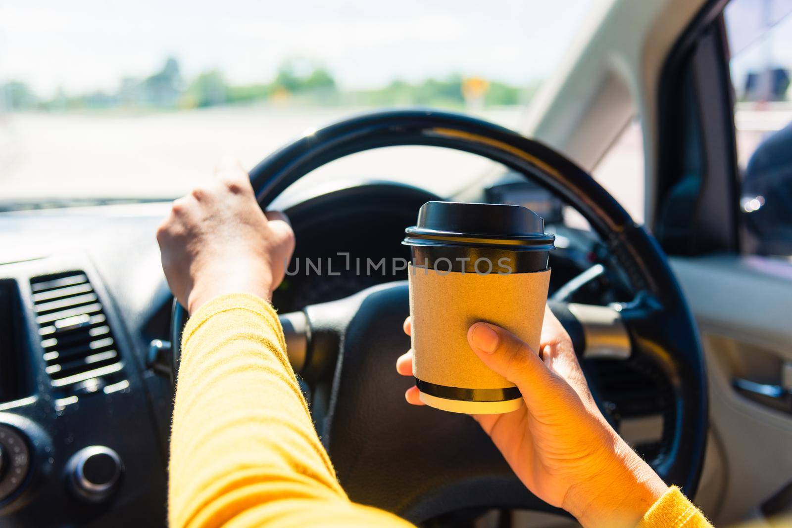 Asian woman drinking hot coffee takeaway cup inside a car and while driving the car in the morning during going to work on highway, Transportation and vehicle concept