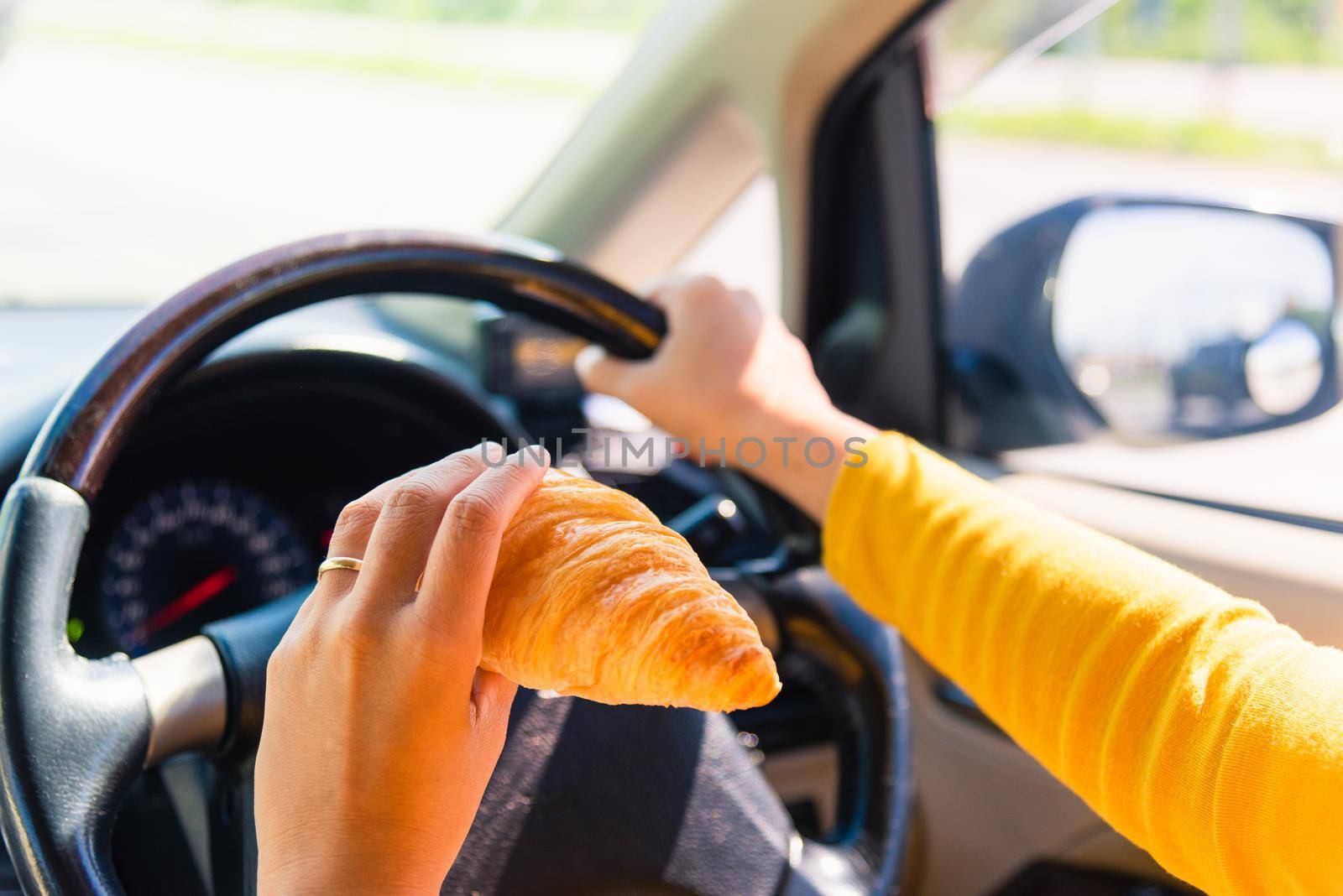 Asian woman eating food fastfood while driving the car in the morning during going to work on highway road, Transportation and vehicle concept