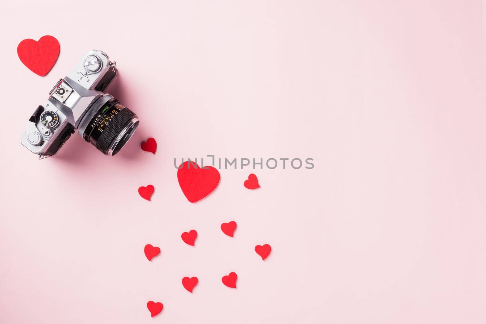 Valentines' day background. Vintage retro camera and red hearts composition greeting card love Valentines day I love photography concept on pink background with copy space. Top View from above