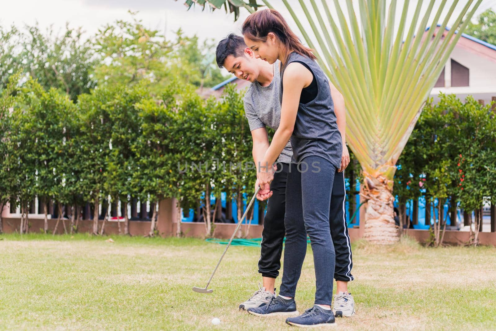 young man support teaching training woman to play perfect golf while standing together by Sorapop